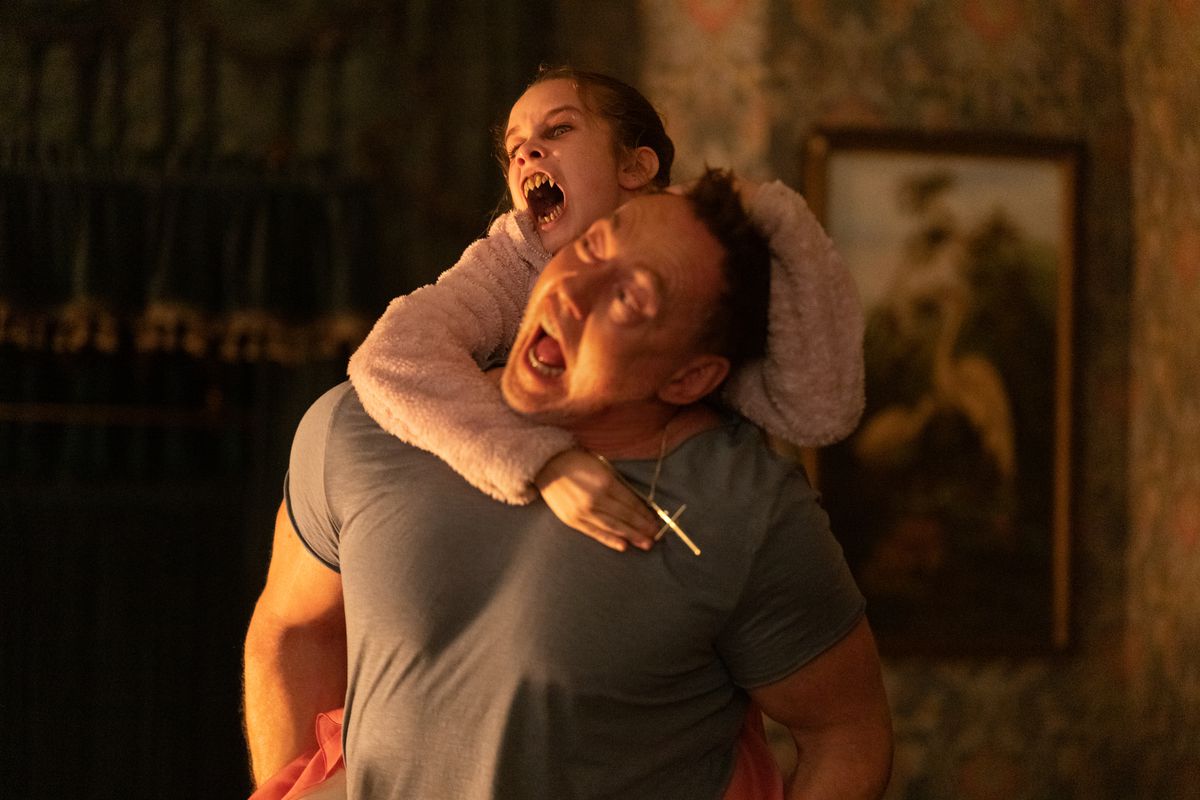 Alisha Weir holds Kevin Durand's back and tries to bite him into Abigail with her vampire sharp teeth