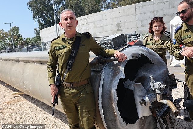 Israeli military spokesman Admiral Daniel Hagari (L) poses next to an Iranian ballistic missile that fell in Israel over the weekend during a media tour of the Julis military base near the southern Israeli city of Kiryat Malachi on April 16, 2024