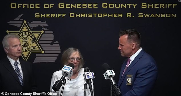 The victim's daughter (center) became emotional as the video was shown at a news conference also attended by Genesee County Sheriff Chris Swanson (right) and Prosecutor David Leyton (left).