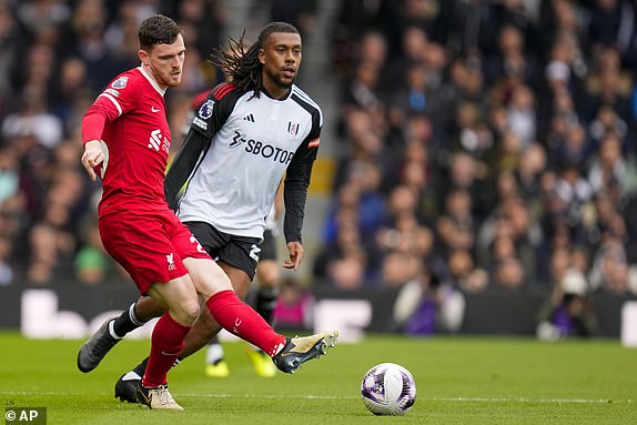 Liverpool's Andrew Robertson, front, duels for the ball with Fulham's Alex Iwobi during the English Premier League football match between Fulham and Liverpool at Craven Cottage Stadium in London, Sunday, April 21, 2024. (AP Photo/Kirsty Wigglesworth)