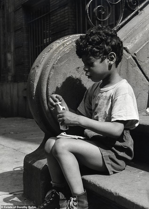 A young boy opening a package of candy in New York in 1952