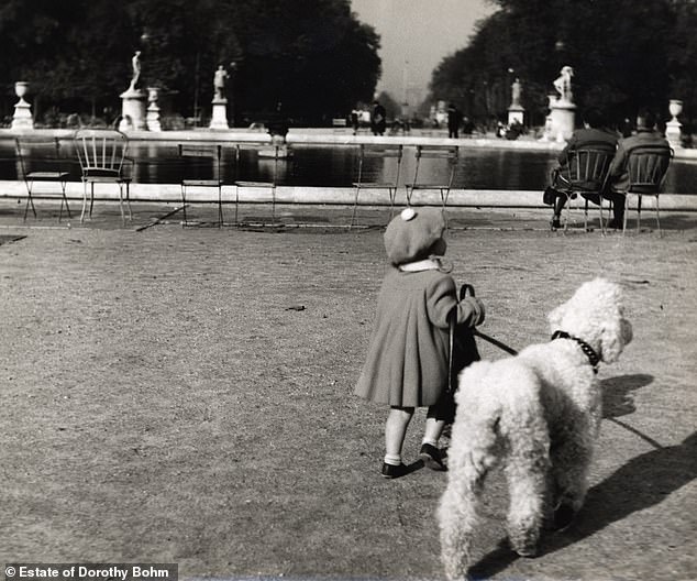 A little girl walks her dog in the Jardin des Tuileries, Paris, 1953