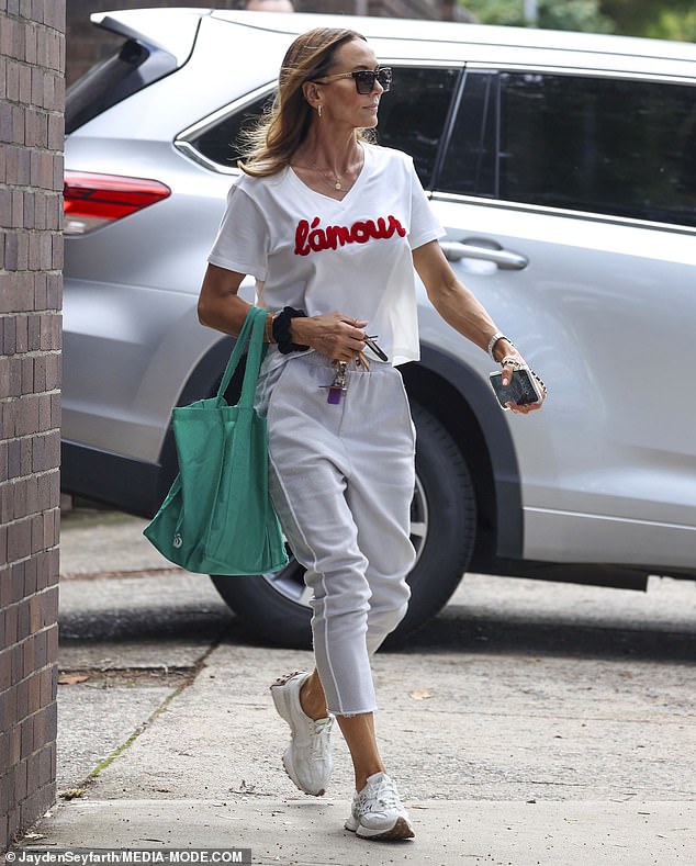 The former WAG, 42, looked effortlessly stylish in a white 'L'amour' top and matching white trousers which showed off her slim figure and flawless tan