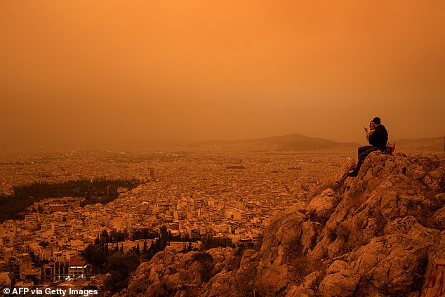 A couple pictured sitting on Tourkovounia Hill as the southerly wind brought waves of Saharan dust.  The Mars-like filter will be short-lived, however, with skies expected to clear on Wednesday as winds change