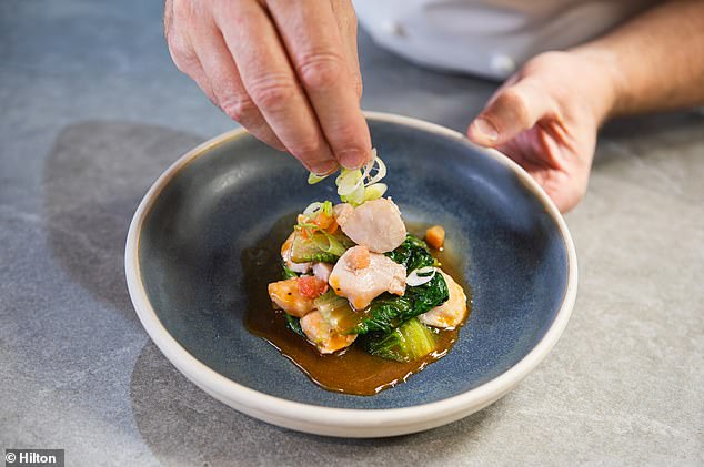 A Hilton chef prepares poached Scottish salmon cheeks with seaweed stock, asparagus stalks and tomato