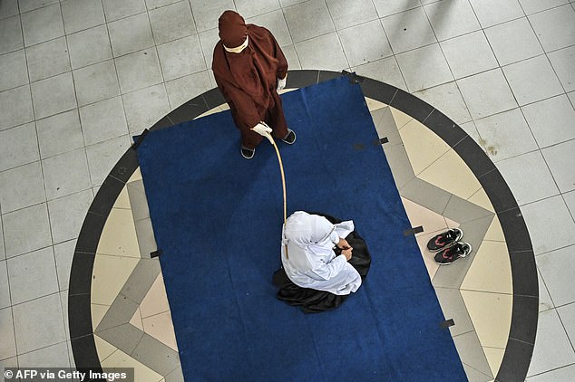 A member of Sharia police canes a woman after she was allegedly caught near a man, in violation of the region's strict laws