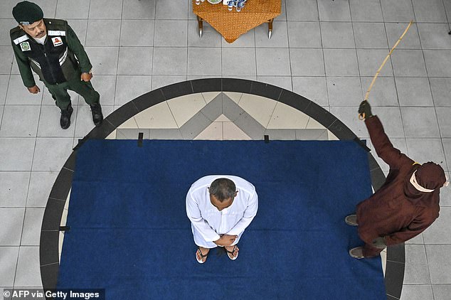 A man (in white) is caned by a member of the Sharia police as punishment for being caught with a woman in Banda Aceh