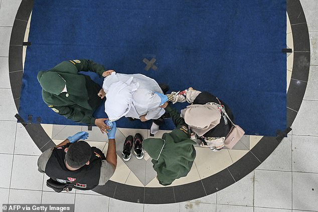 Medics check on a woman after she is caned as punishment for breaking strict gender relations laws