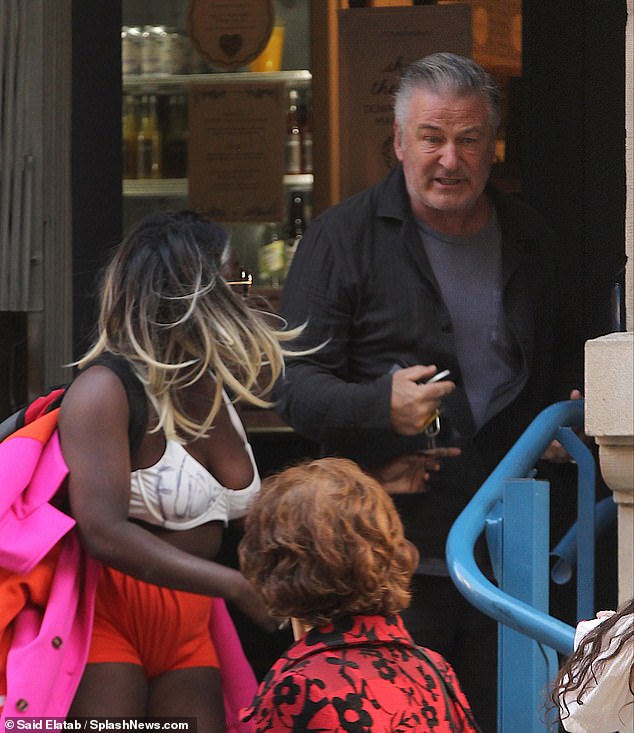 An angry-looking Baldwin stops in the doorway and tries to get away from her