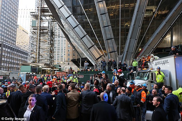 Construction site workers gathered outside, while others stood on the scaffolding to catch a glimpse