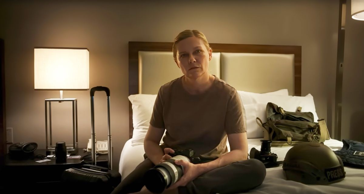 Photojournalist Lee (Kirsten Dunst) sits on a hotel room bed and stares directly into the camera in Alex Garland's Civil War