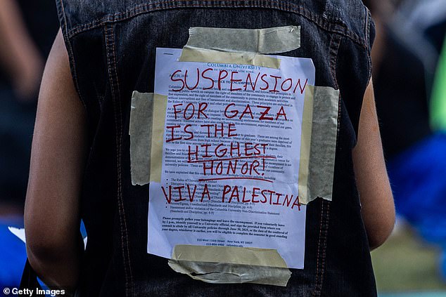 A protester carries a university disciplinary notice, overlaid with support for the Palestinians in Gaza at Columbia University