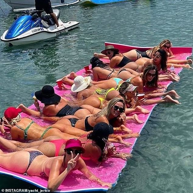 A group of women in bikinis were seen lying on their stomachs on top of a long pink float in the crystal blue water