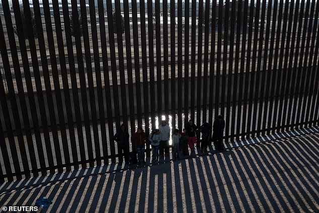 Pictured: A drone shot shows migrants from South and Central America as they line up against the border wall to surrender to border officials after gaining entry into El Paso, Texas from Ciudad Juarez, Mexico