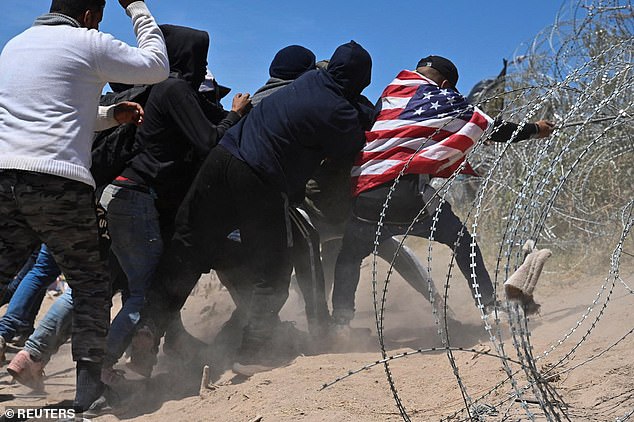 Pictured: Migrants attempt to cross concertina wire at the US-Mexico border near El Paso, Texas