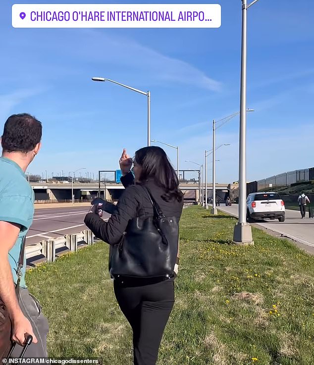 An angry female traveler gave the middle finger to protesters as she walked to the airport and shouted: 'F*** you!'