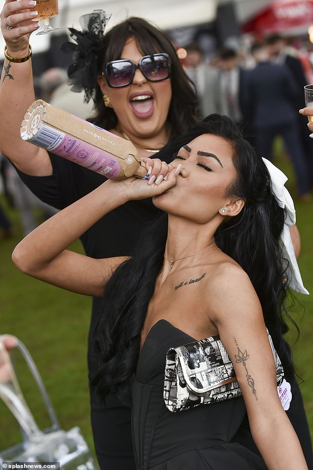 Happier scenes: A woman is shown drinking from the bottle as her friend cheers her on in Liverpool today