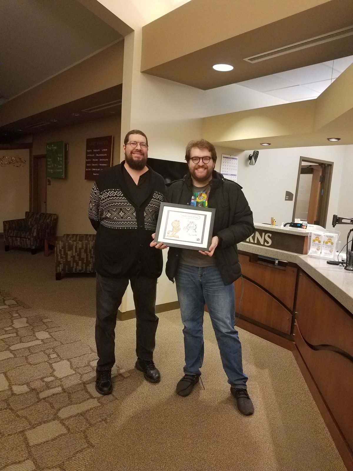 Russ and Quinton Hoover stand side by side with a framed drawing of Garfield.