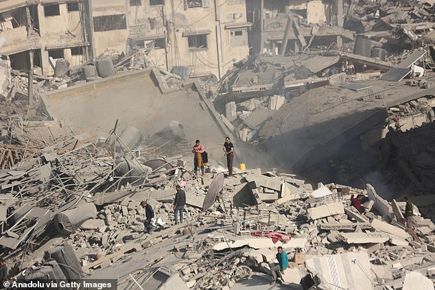 Palestinians gather around the burned and destroyed Al-Shifa Hospital in Deir Al-Balah, Gaza on April 1, 2024.  Many buildings, including the hospital, have been severely damaged by air raids