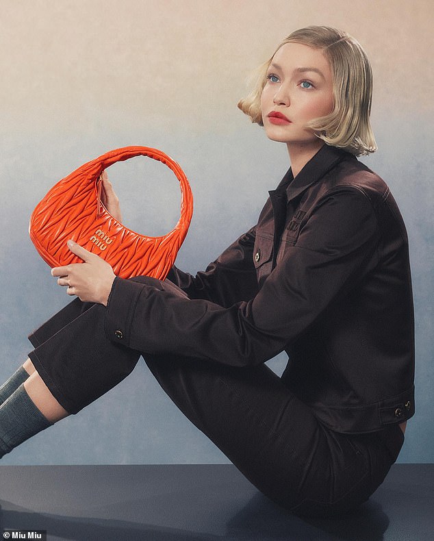 She modeled one of the brand's striking orange purses