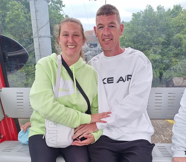 Mark Downey, 45, from Bolton, Manchester, pictured with his partner Samantha Scott, 39, suffered an excruciating headache in September 2023 while driving with his family to a holiday in Wales.