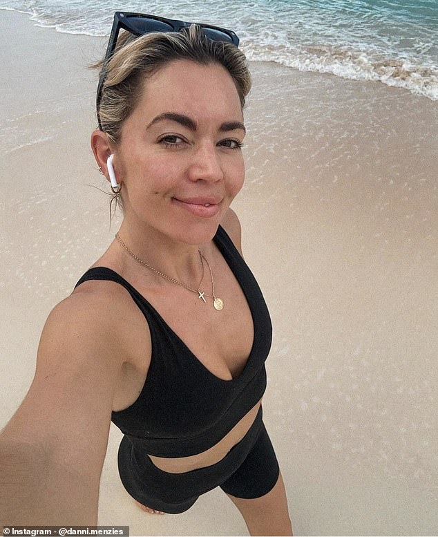 More photos showed Danni taking a selfie as she walked along the beach wearing a black crop top and shorts