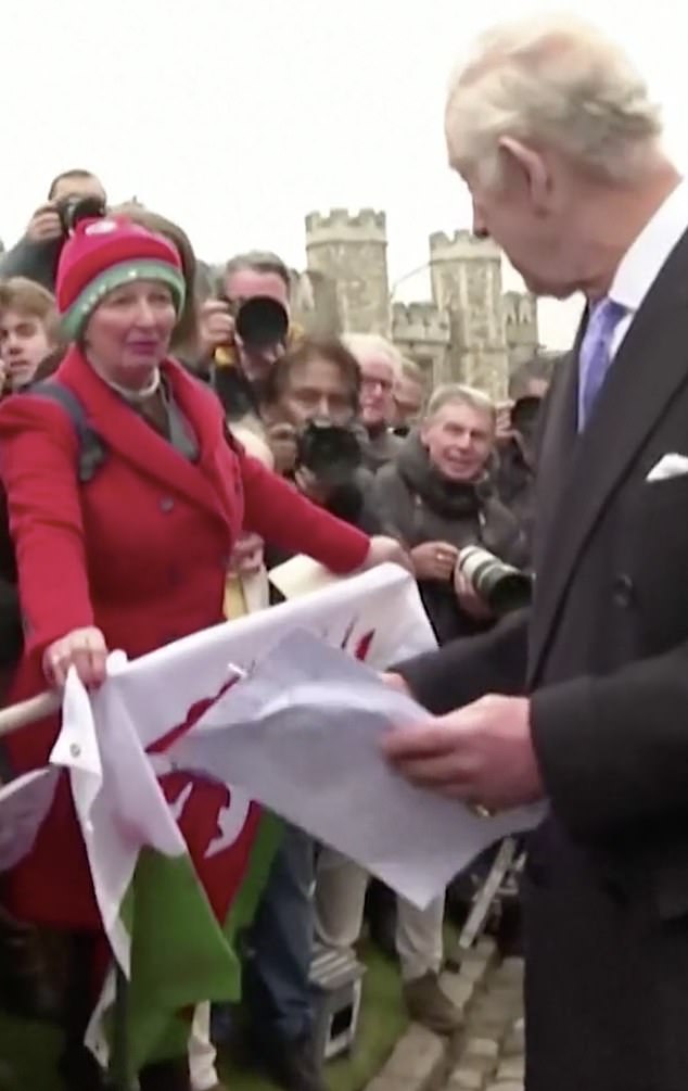 A woman, holding a Welsh flag and wearing a matching bright red coat and hat, called King to get his attention