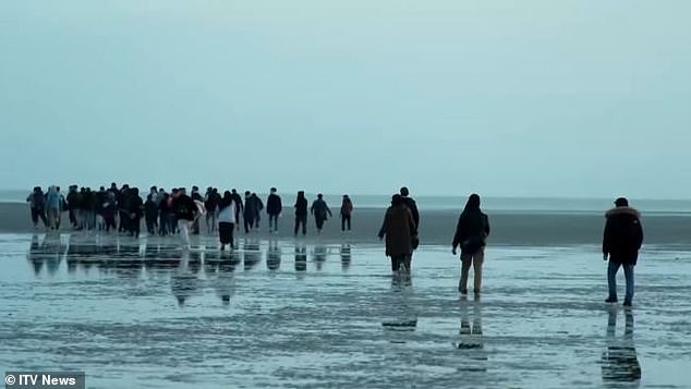 A large group of migrants were seen sprinting across a beach before climbing onto a small rubber boat as they prepared to head towards Britain, in front of UK-funded French police.