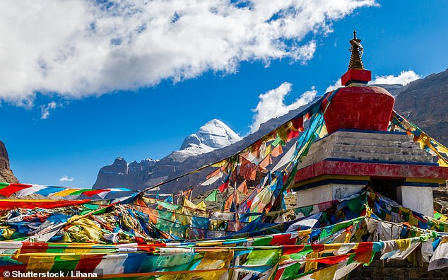 Colorful prayer flags flutter in the wind, with the south side of Mount Kailash in the background