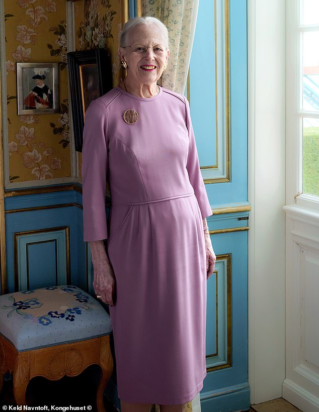 Queen Margrethe poses in one of the rooms of Fredensborg Castle, leaning against beautifully decorated teal walls