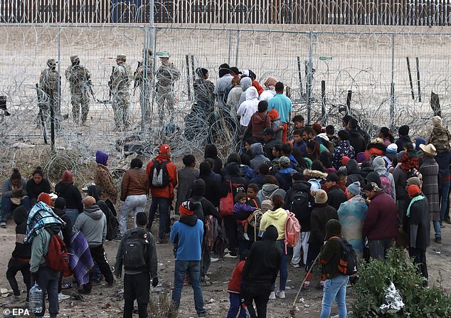 Pictured: Migrants gather as they attempt to enter US territory through the razor fence at the border in Ciudad Juarez, Chihuahua state, northern Mexico