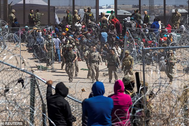 Texas State Troopers walk to a fence after hundreds of migrants broke through razor wire to illegally enter the US last month