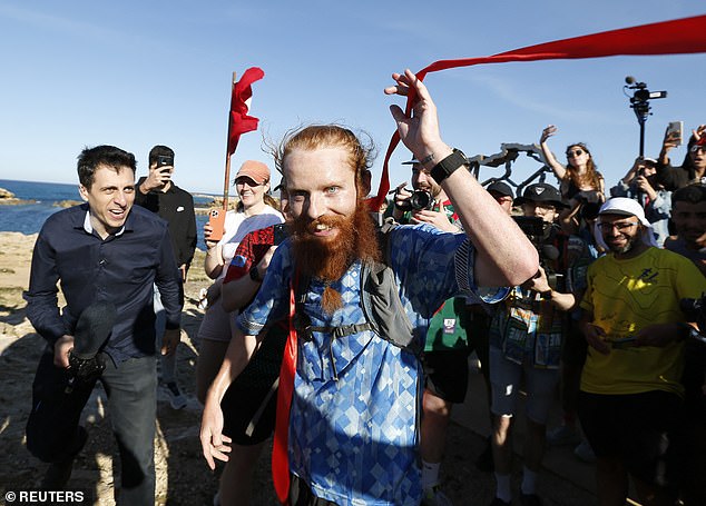 Russ Cook beams as he crosses the finish line after becoming the first person to run the length of Africa