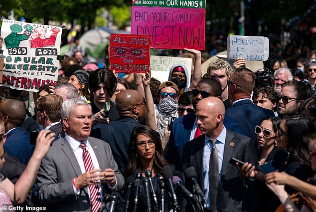 Comer (left) addresses a crowd of activists and media next to Boebert (center) on the street outside GWU