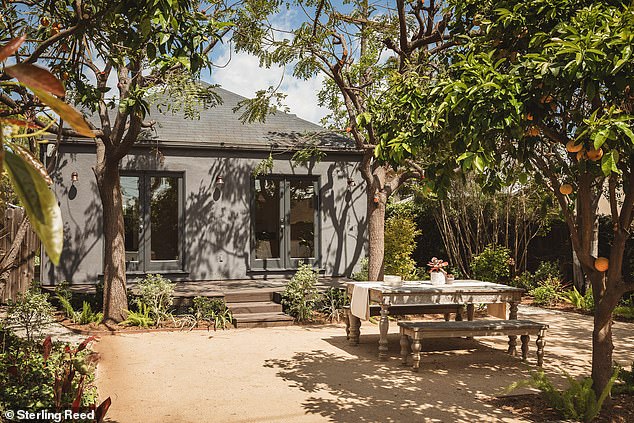 The home's enormous backyard features a half-moon deck, surrounded by lush greenery and beautiful fruit trees