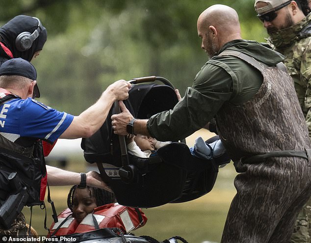 A child in a car seat is removed from a boat as residents are evacuated from their homes by boat by Montgomery County Sheriff's Office deputies