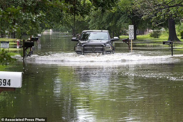 A pick-up truck maneuvers through a waterlogged residential street in Woodloch