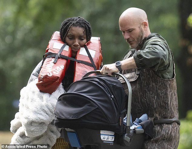 A woman is handed her child after being evacuated from her home by boat with the help of officers from the Montgomery County Sheriff's Office