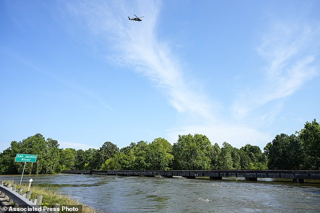 A helicopter flies above the San Jacinto River, which burst its banks after a heavy storm