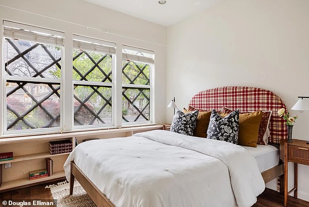 The first bedroom showcases the bold cross-window design from within and fits perfectly above a permanent bookshelf and next to a cozy bed with a checkered headboard