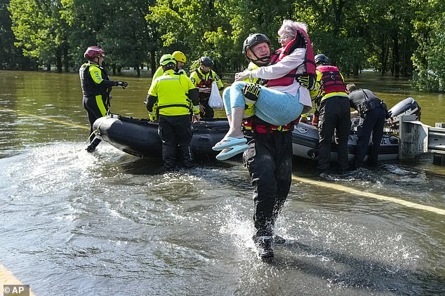 A Conroe firefighter is seen helping an elderly woman to safety after her home flooded in Conroe, Texas