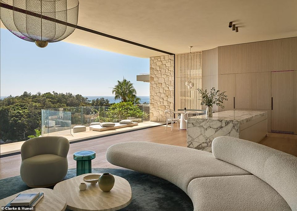 An informal dining area with curved seating adjoins an overhanging curved balcony;  hidden cabinets in the wood paneling hide the kitchen storage, refrigerator and bar