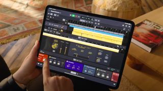 A hand holding an iPad running Logic Pro