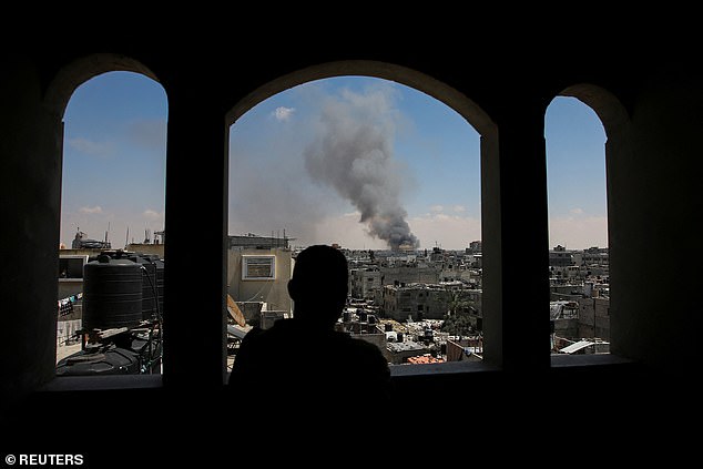 A Palestinian man watches smoke rise from Israeli attacks as Israeli forces launch a ground and air operation in the eastern part of Rafah