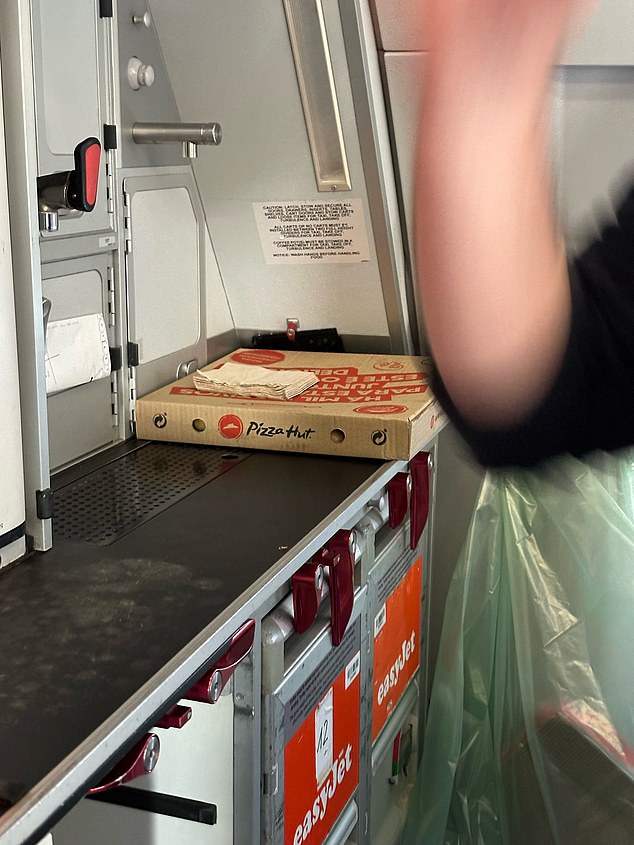 A photo sent to MailOnline shows a pizza box placed on a shelf in the plane's crew compartment after the plane was delayed so the crew could get food for the flight from Lisbon to Manchester