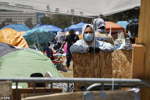 A person stands among tents set up in an encampment of pro-Palestinian protesters on the UCLA campus