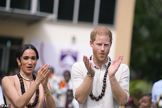 Harry and Meghan clap today as they meet children at the Wuse Lightway Academy in Abuja