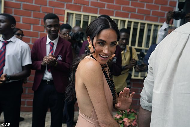 Meghan Markle waves as she and Harry visit the Wuse Lightway Academy in Abuja today