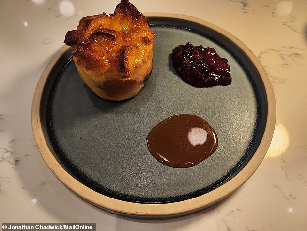 Bread and butter pudding made with leftover jam and pastries, served with blueberries and fudge, caramel sauce