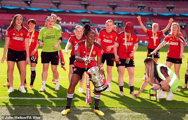 Melvine Malard raises the trophy as United players celebrate their victory on Sunday